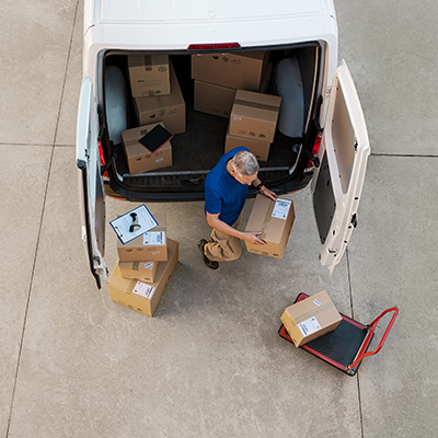 Courier Delivering Parcel From Back Of White Van