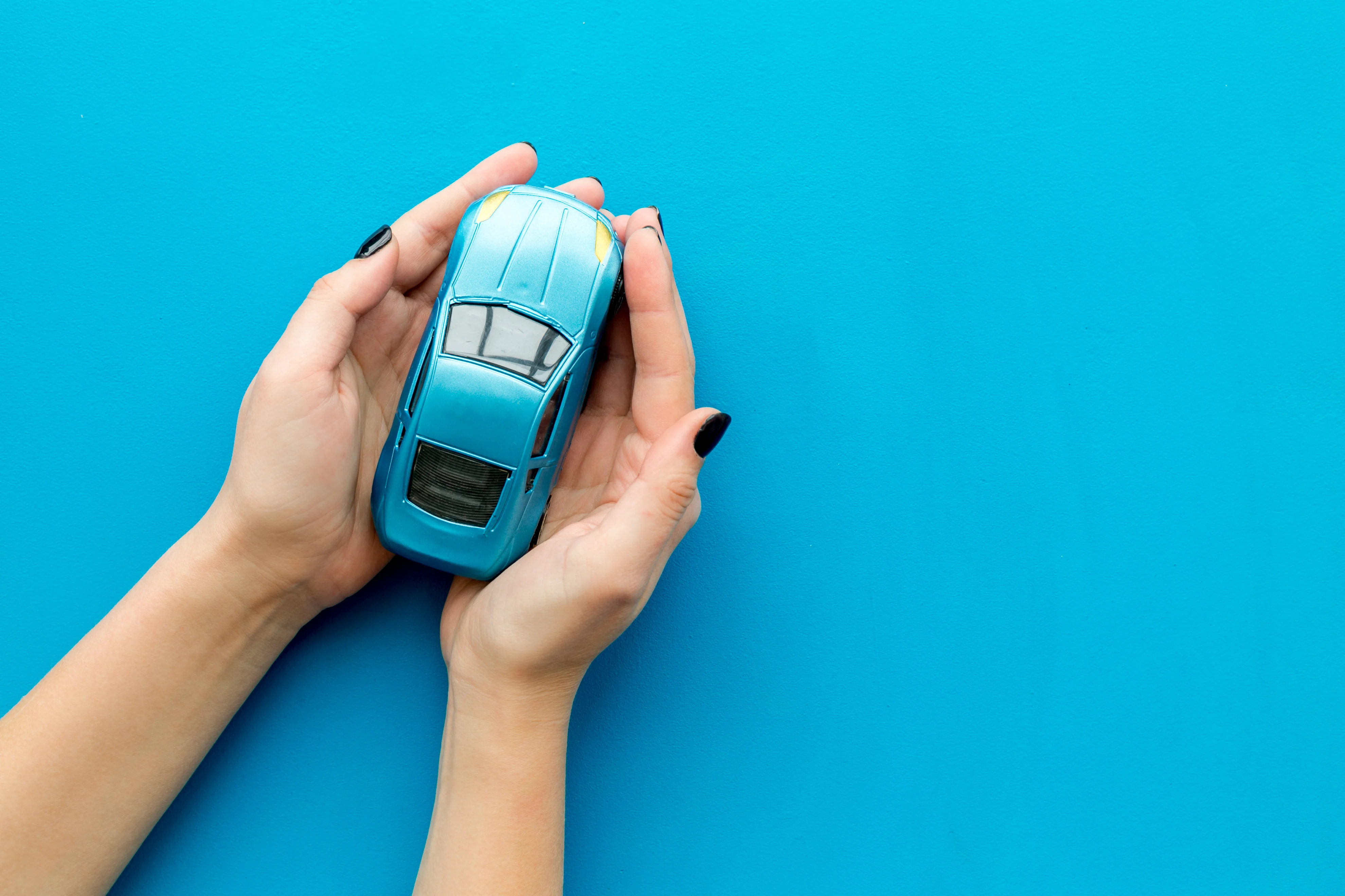 Top View Of Toy Car In Female Hands With Blue Background