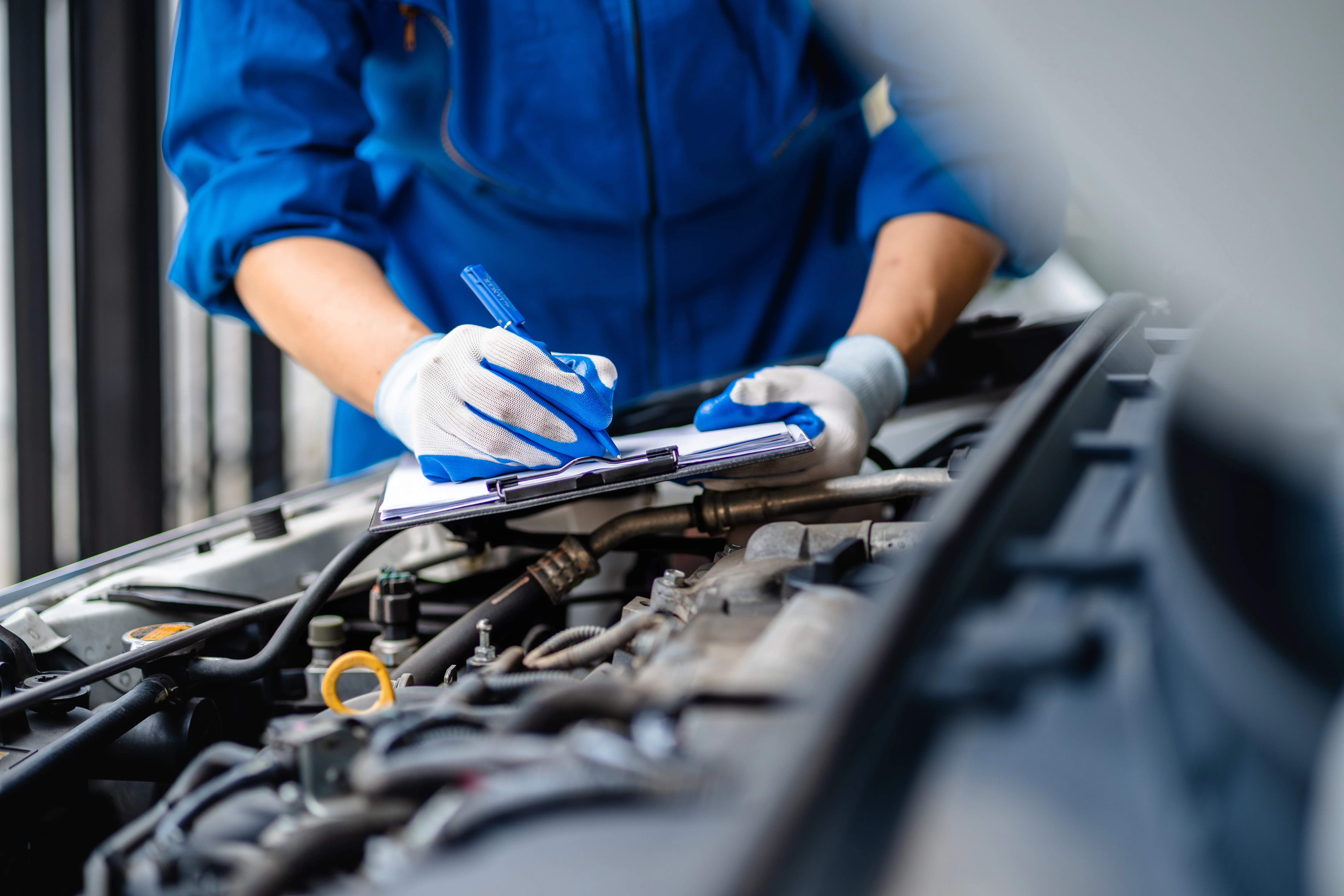 Mechanic With Clipboard Checking The Engine Of A Car