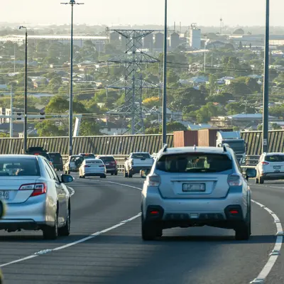 Cars Driving Along A Busy Motorway Overlooking Industrial Skyline